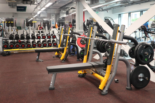 New weights at the Indoor Sports Centre. Pictured are two weights benches with weights and weights bars and a rack of dumbbells, in front of a mirror.